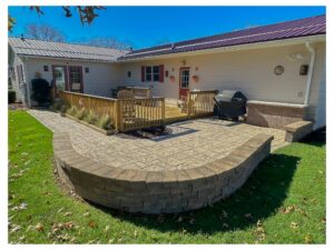 Stamped concrete patio with curved retaining wall and deck built by a landscaping company in Indiana PA.