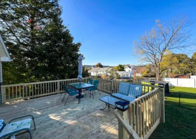 wood deck with patio furniture on it in a shady backyard