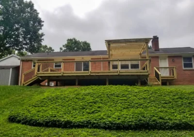 raised deck connected to a home with a yard and plants sloping down away from it