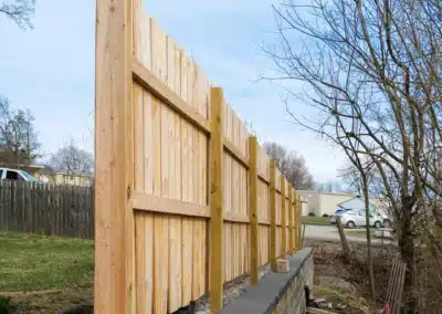 wood fence beside trees and a lawn