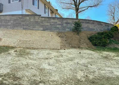 large stone block retaining wall beside a hillside and tree