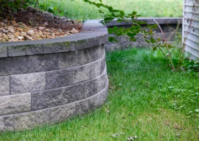 curved stone block retaining wall beside a yard